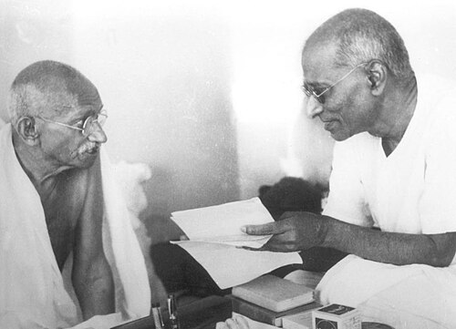 Gandhi seated at left and Rajaji at right, working over papers at a low desk.