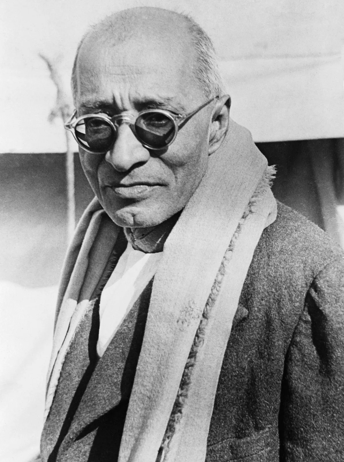 C. Rajagopalachari in 1948, wearing dark glasses, a woollen coat and a heavy shawl, photographed outdoors.